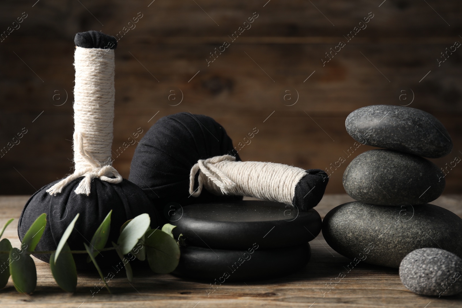 Composition with herbal bags and spa stones on wooden table, closeup Photo of Composition with herbal bags and spa stones on wooden table, closeup
