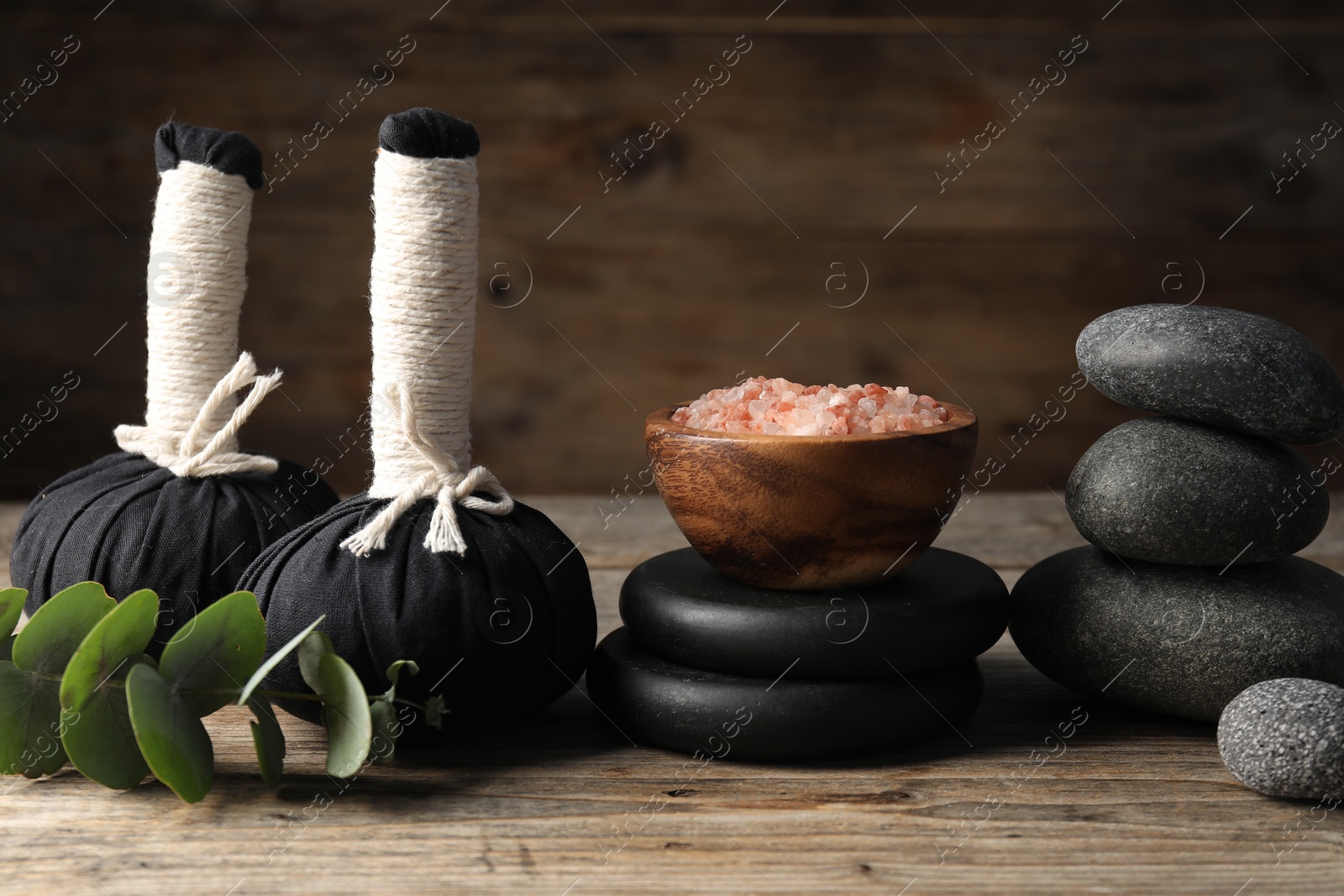 Composition with herbal bags and spa stones on wooden table, closeup Photo of Composition with herbal bags and spa stones on wooden table, closeup
