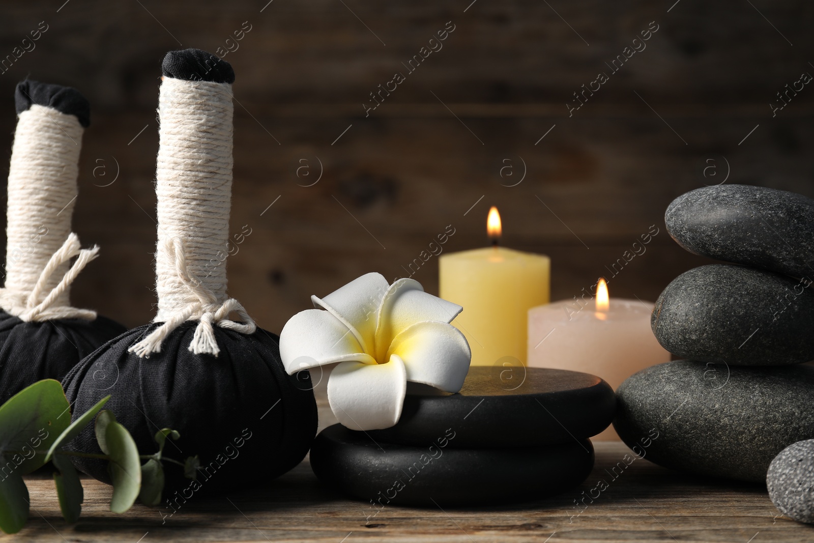 Composition with herbal bags and spa stones on wooden table, closeup Photo of Composition with herbal bags and spa stones on wooden table, closeup