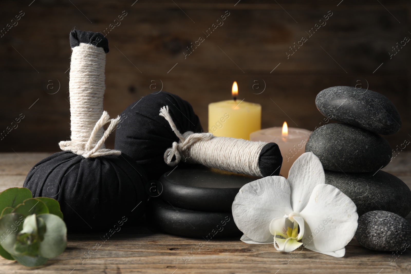 Composition with herbal bags and spa stones on wooden table, closeup Photo of Composition with herbal bags and spa stones on wooden table, closeup