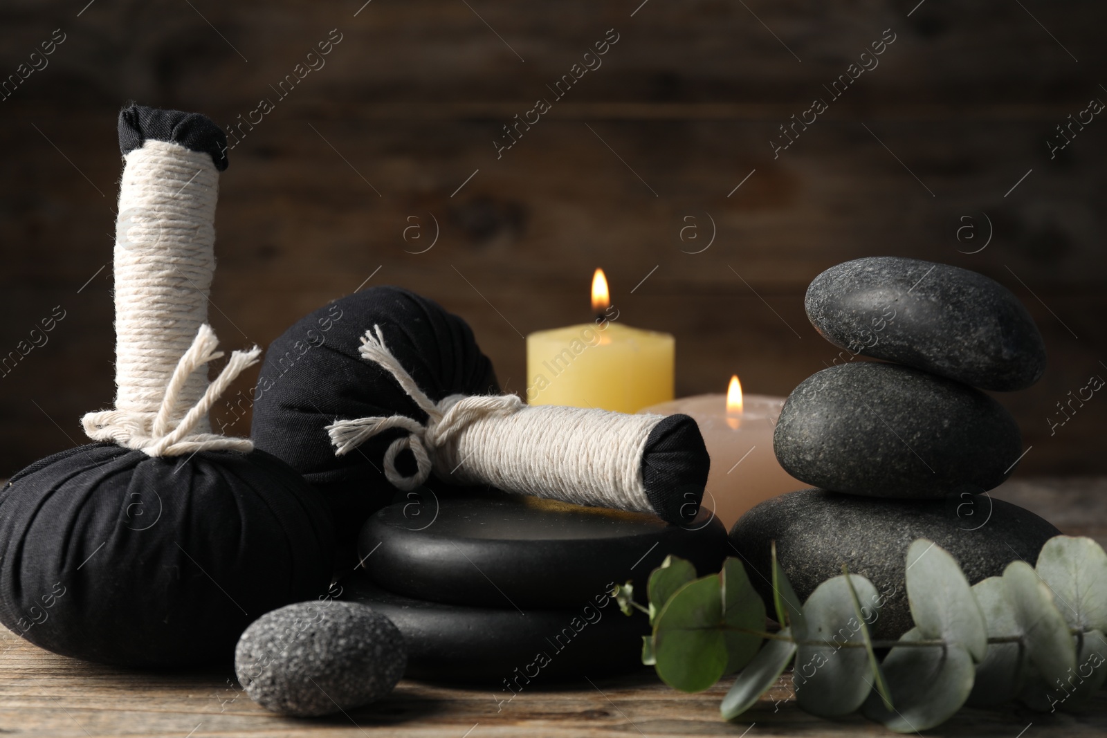 Photo of Composition with herbal bags and spa stones on wooden table, closeup