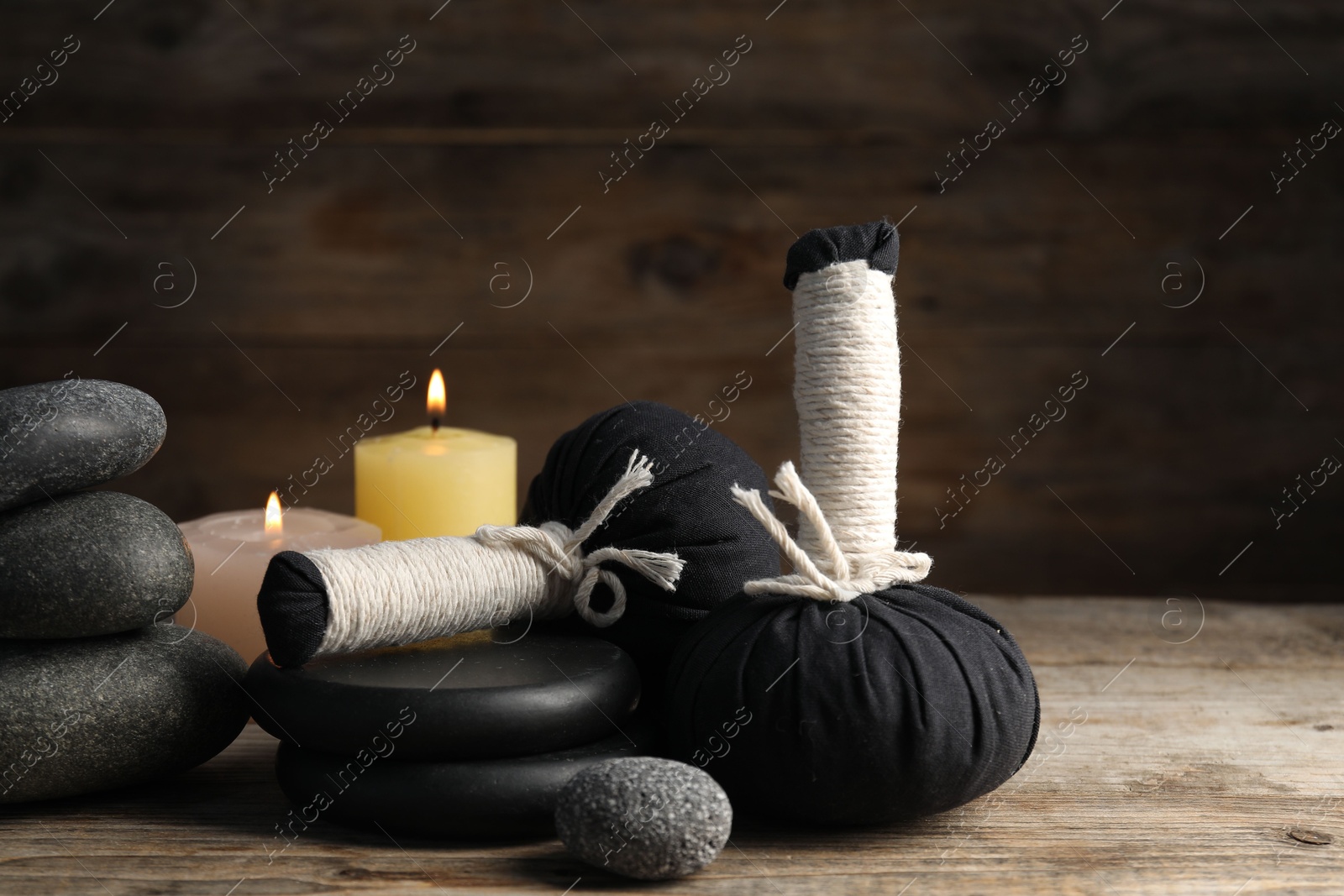 Composition with herbal bags and spa stones on wooden table, closeup Photo of Composition with herbal bags and spa stones on wooden table, closeup