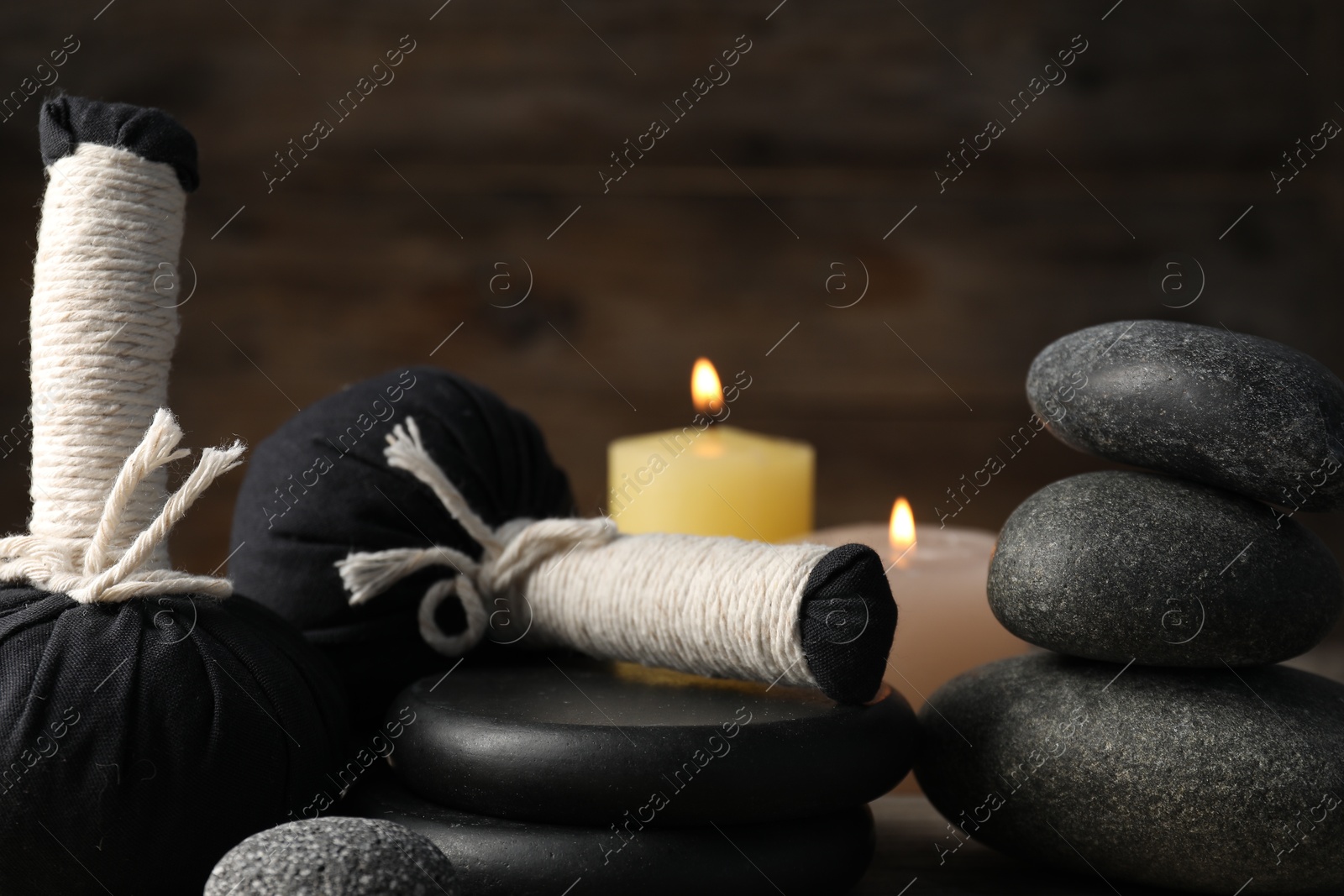 Composition with herbal bags and spa stones on wooden table, closeup Photo of Composition with herbal bags and spa stones on wooden table, closeup
