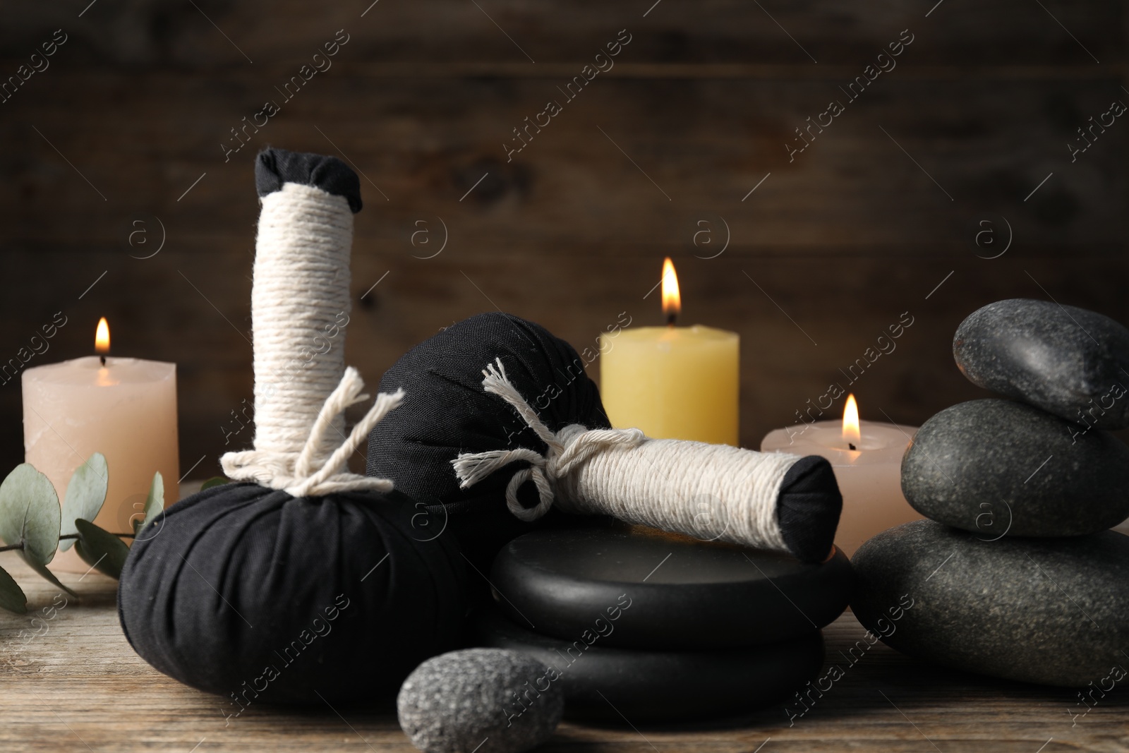 Composition with herbal bags and spa stones on wooden table, closeup Photo of Composition with herbal bags and spa stones on wooden table, closeup