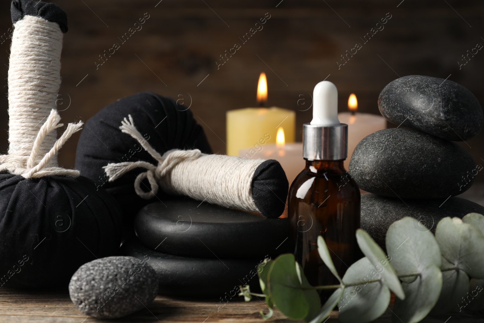 Photo of Composition with cosmetic product, spa stones and herbal bags on wooden table, closeup