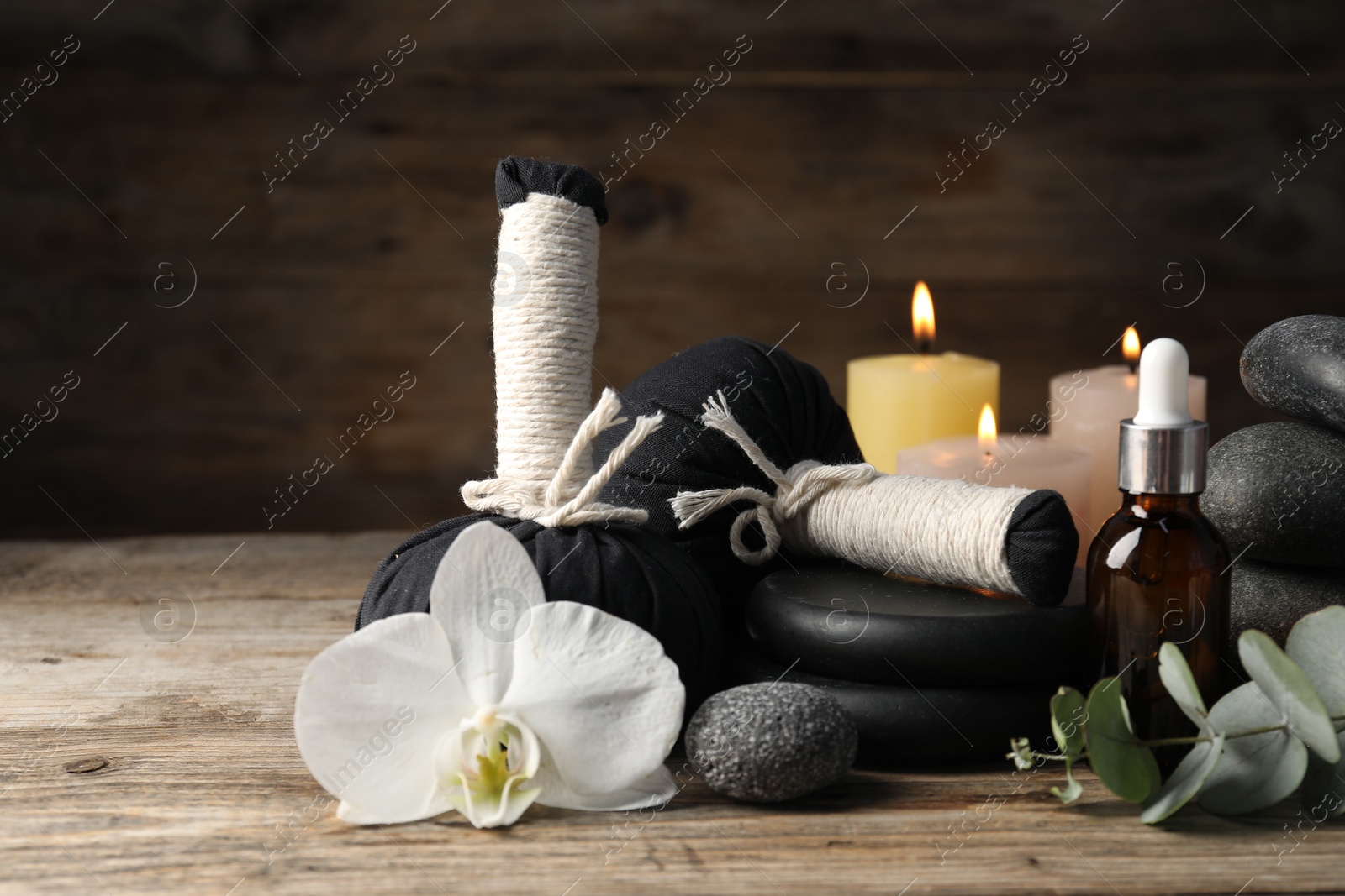 Composition with cosmetic product, spa stones and herbal bags on wooden table, closeup Photo of Composition with cosmetic product, spa stones and herbal bags on wooden table, closeup