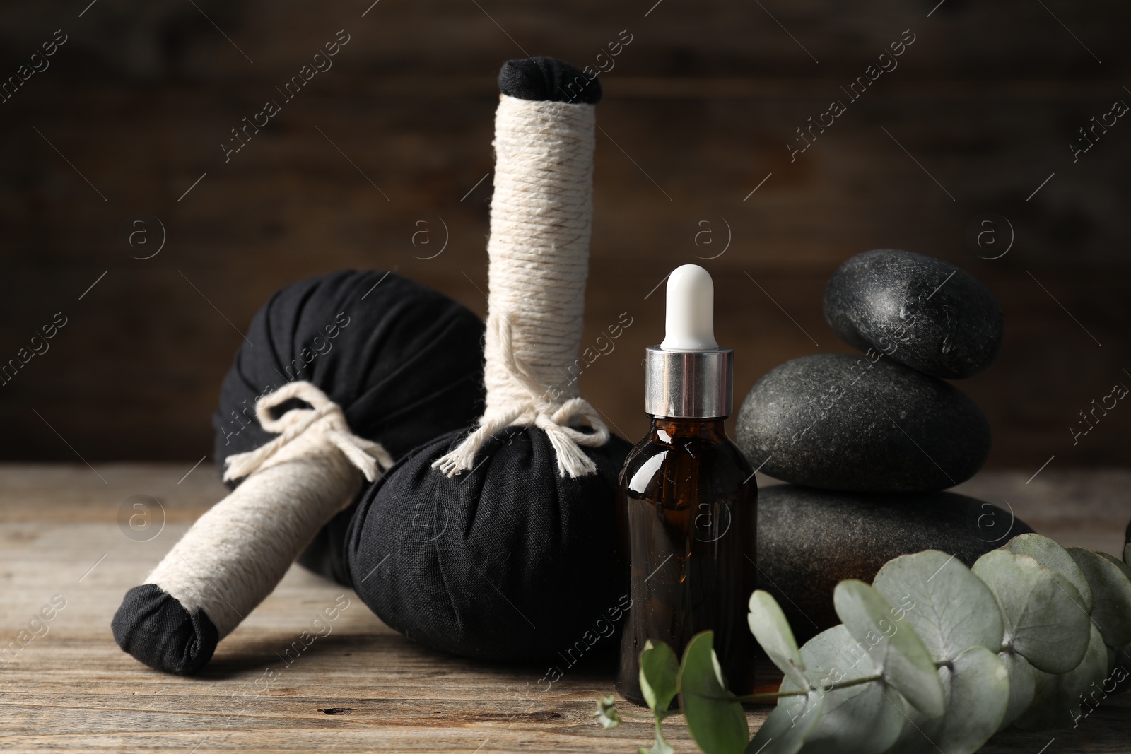 Composition with cosmetic product, spa stones and herbal bags on wooden table, closeup Photo of Composition with cosmetic product, spa stones and herbal bags on wooden table, closeup