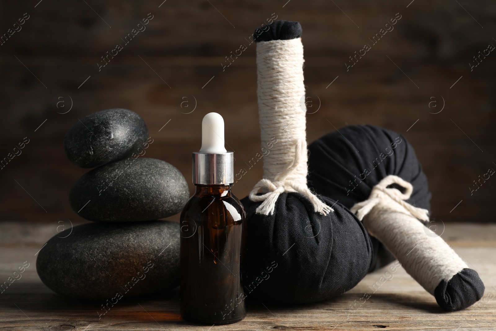Composition with cosmetic product, spa stones and herbal bags on wooden table, closeup Photo of Composition with cosmetic product, spa stones and herbal bags on wooden table, closeup
