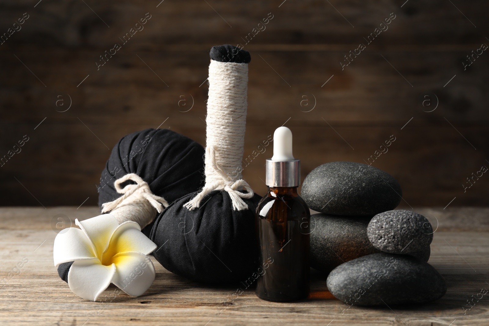 Composition with cosmetic product, spa stones and herbal bags on wooden table, closeup Photo of Composition with cosmetic product, spa stones and herbal bags on wooden table, closeup
