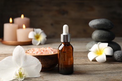 Photo of Composition with cosmetic product and spa stones on wooden table, closeup