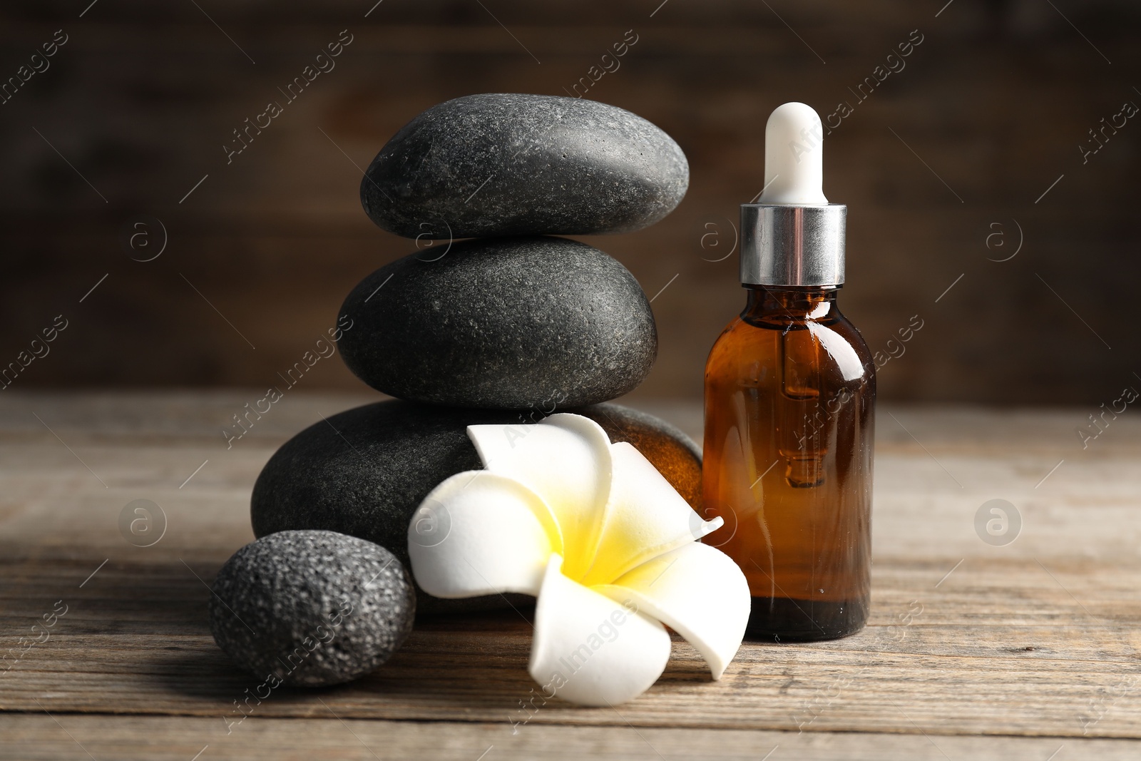 Spa stones, cosmetic product and plumeria flower on wooden table, closeup Photo of Spa stones, cosmetic product and plumeria flower on wooden table, closeup