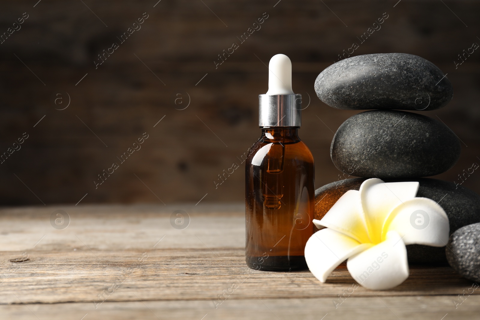 Spa stones, cosmetic product and plumeria flower on wooden table, closeup. Space for text Photo of Spa stones, cosmetic product and plumeria flower on wooden table, closeup. Space for text