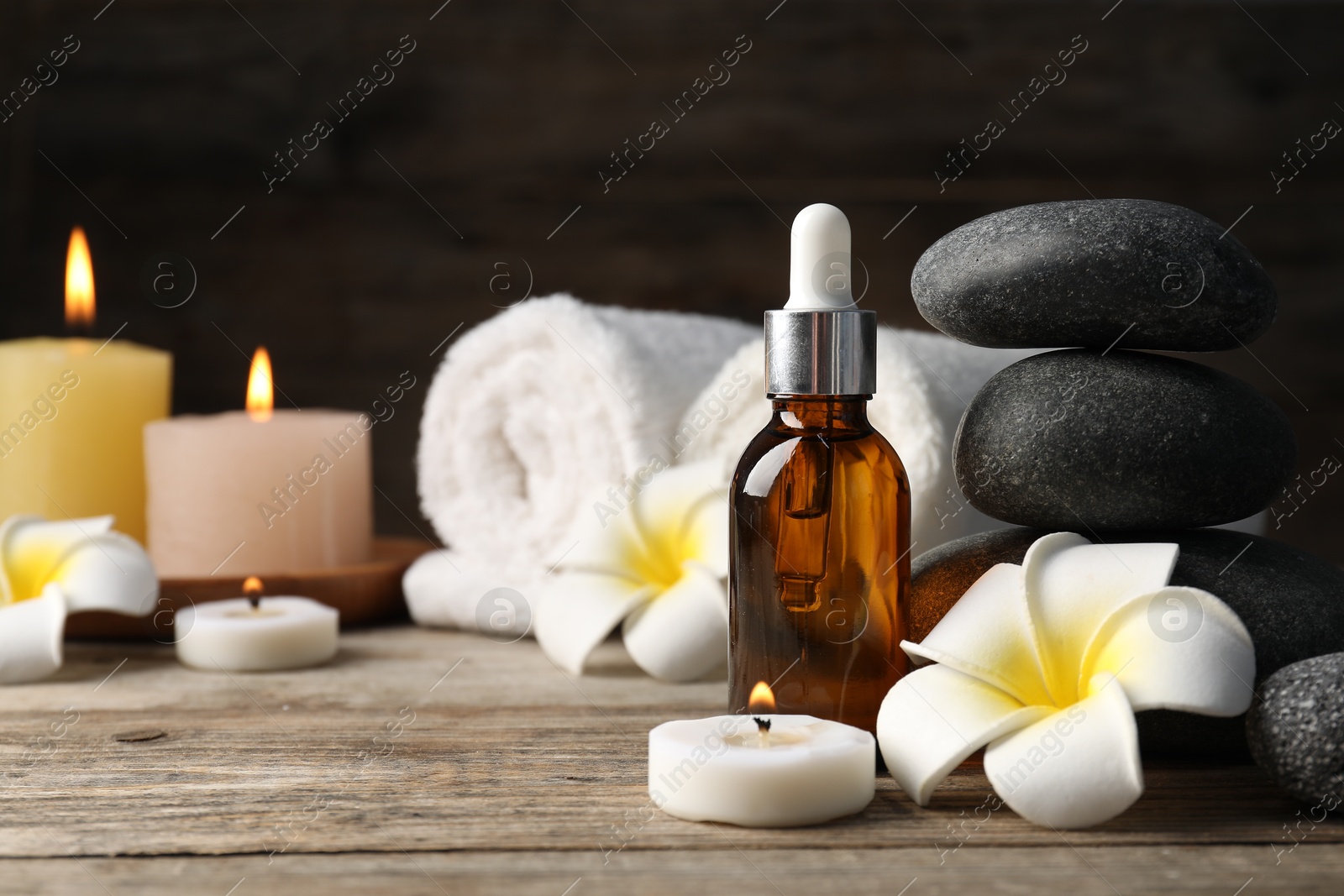 Photo of Composition with cosmetic product and spa stones on wooden table, closeup