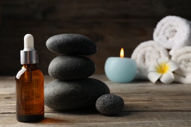 Photo of Composition with cosmetic product and spa stones on wooden table, closeup