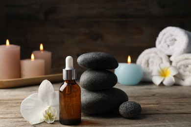 Photo of Composition with cosmetic product and spa stones on wooden table, closeup