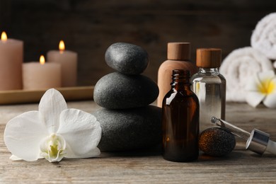Photo of Composition with cosmetic products and spa stones on wooden table, closeup