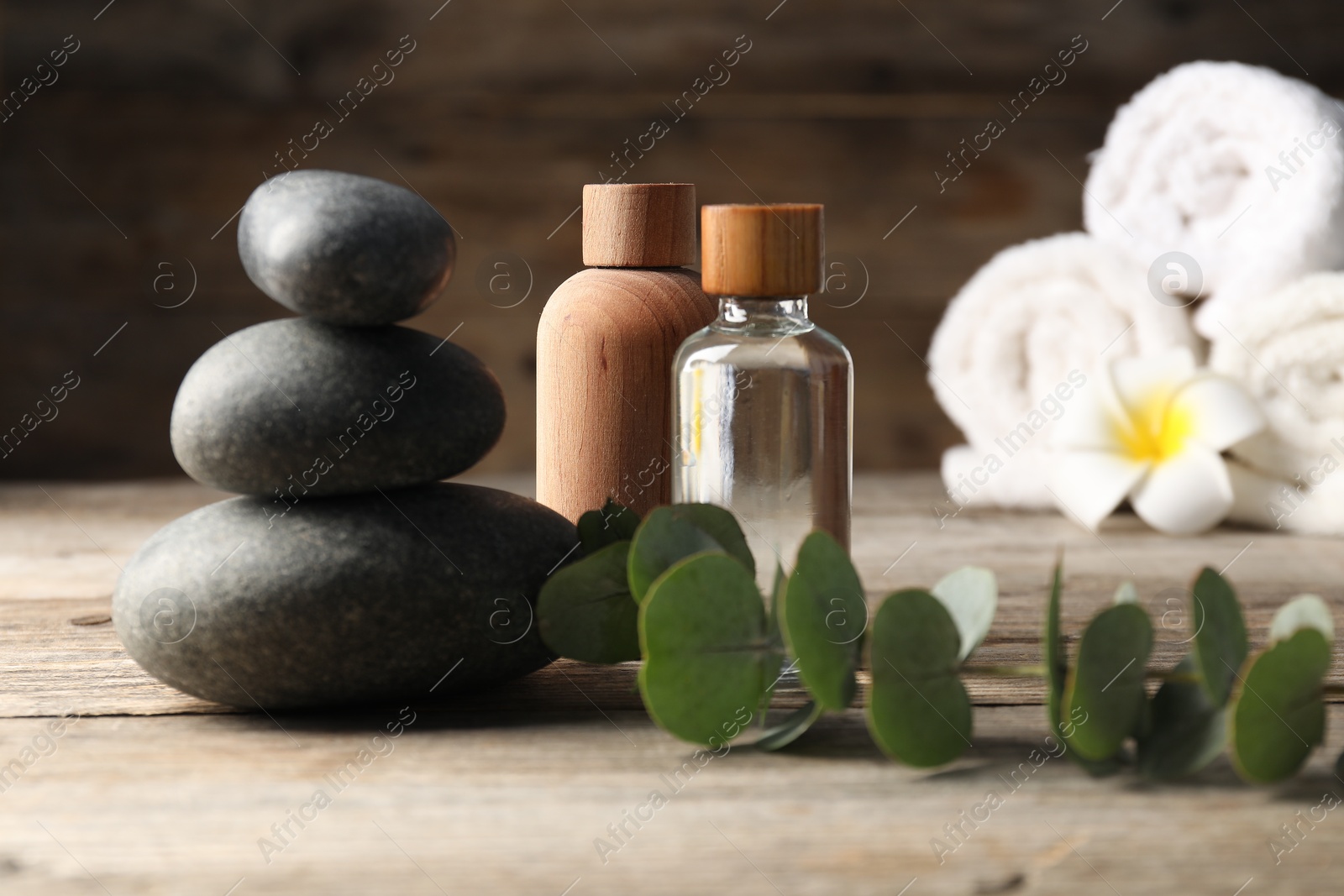 Composition with cosmetic products and spa stones on wooden table, closeup Photo of Composition with cosmetic products and spa stones on wooden table, closeup