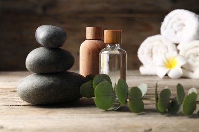 Photo of Composition with cosmetic products and spa stones on wooden table, closeup