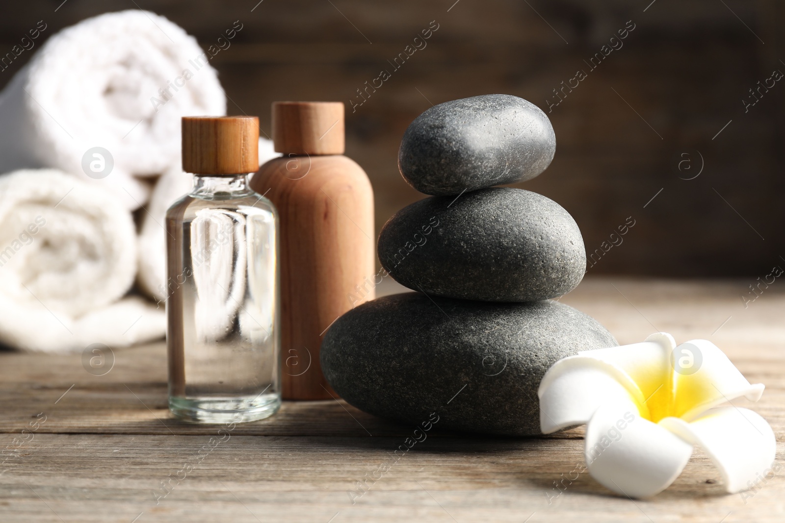 Composition with cosmetic products and spa stones on wooden table, closeup Photo of Composition with cosmetic products and spa stones on wooden table, closeup