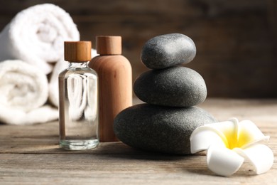 Photo of Composition with cosmetic products and spa stones on wooden table, closeup