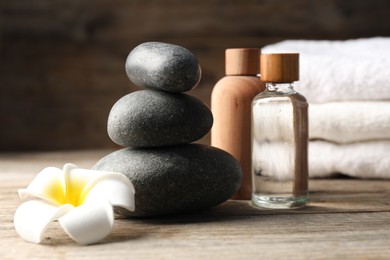 Photo of Composition with cosmetic products and spa stones on wooden table, closeup