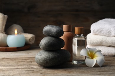 Photo of Composition with cosmetic products and spa stones on wooden table, closeup