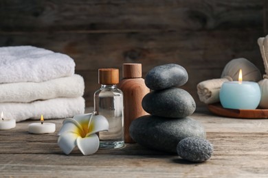 Photo of Composition with cosmetic products and spa stones on wooden table, closeup