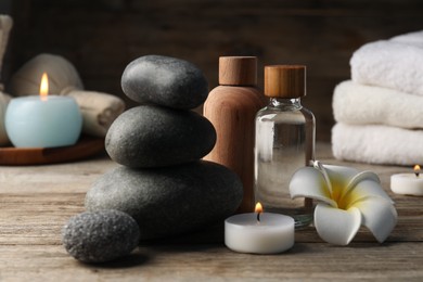Photo of Composition with cosmetic products and spa stones on wooden table, closeup