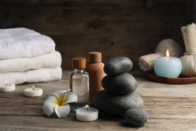 Photo of Composition with cosmetic products and spa stones on wooden table, closeup