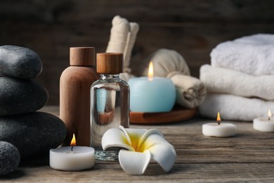 Photo of Composition with cosmetic products and spa stones on wooden table, closeup