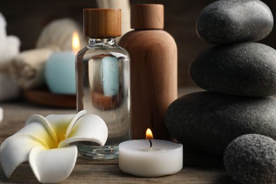 Photo of Composition with cosmetic products and spa stones on wooden table, closeup