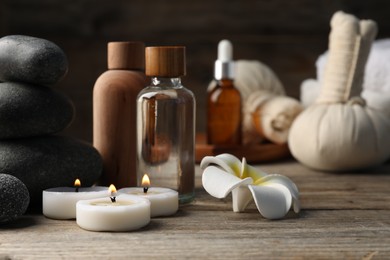 Photo of Composition with cosmetic products and spa stones on wooden table, closeup