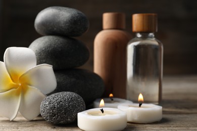 Photo of Composition with cosmetic products and spa stones on wooden table, closeup