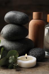 Photo of Composition with cosmetic products and spa stones on wooden table, closeup