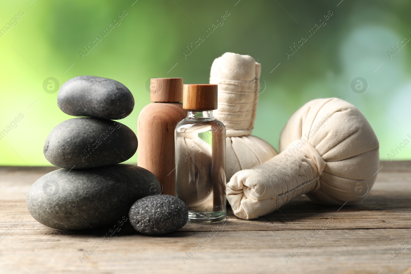 Composition with cosmetic products, spa stones and herbal bags on wooden table, closeup Photo of Composition with cosmetic products, spa stones and herbal bags on wooden table, closeup