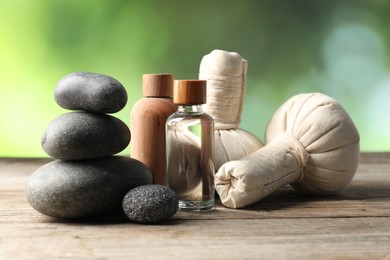 Photo of Composition with cosmetic products, spa stones and herbal bags on wooden table, closeup