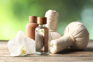 Photo of Cosmetic products, herbal bags and orchid flower on wooden table, closeup