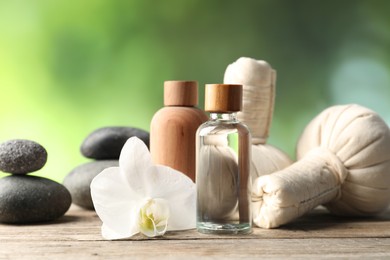 Photo of Composition with cosmetic products, spa stones and herbal bags on wooden table, closeup