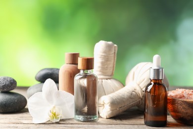Photo of Composition with cosmetic products, spa stones and herbal bags on wooden table, closeup