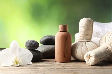 Photo of Composition with cosmetic product, spa stones and herbal bags on wooden table, closeup. Space for text