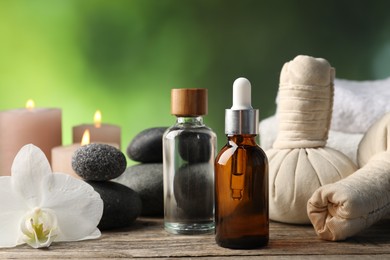 Photo of Composition with cosmetic products, spa stones and herbal bags on wooden table, closeup