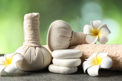 Photo of Composition with spa stones and herbal bags on grey table, closeup