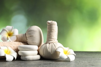 Photo of Composition with spa stones and herbal bags on grey table, closeup. Space for text