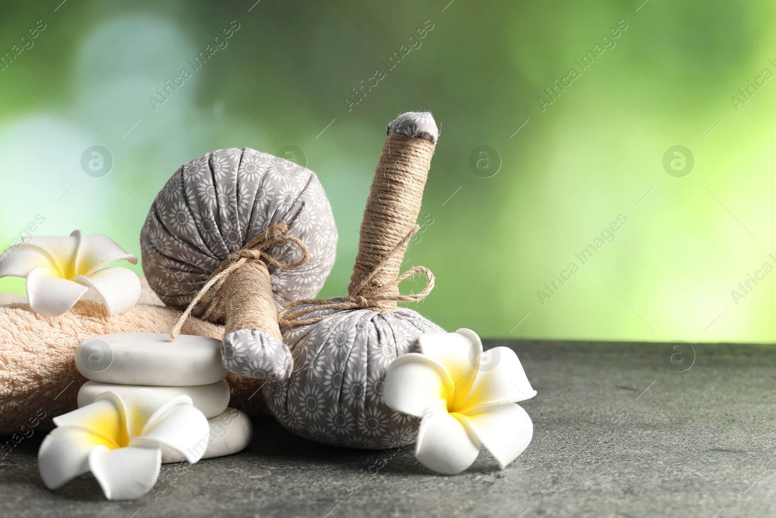 Composition with spa stones and herbal bags on grey table, closeup. Space for text Photo of Composition with spa stones and herbal bags on grey table, closeup. Space for text