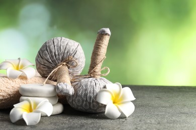 Photo of Composition with spa stones and herbal bags on grey table, closeup. Space for text