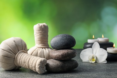 Photo of Composition with spa stones and herbal bags on grey table, closeup
