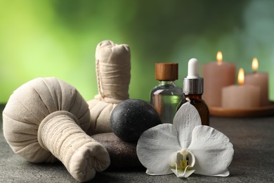 Photo of Composition with spa stones and herbal bags on grey table, closeup