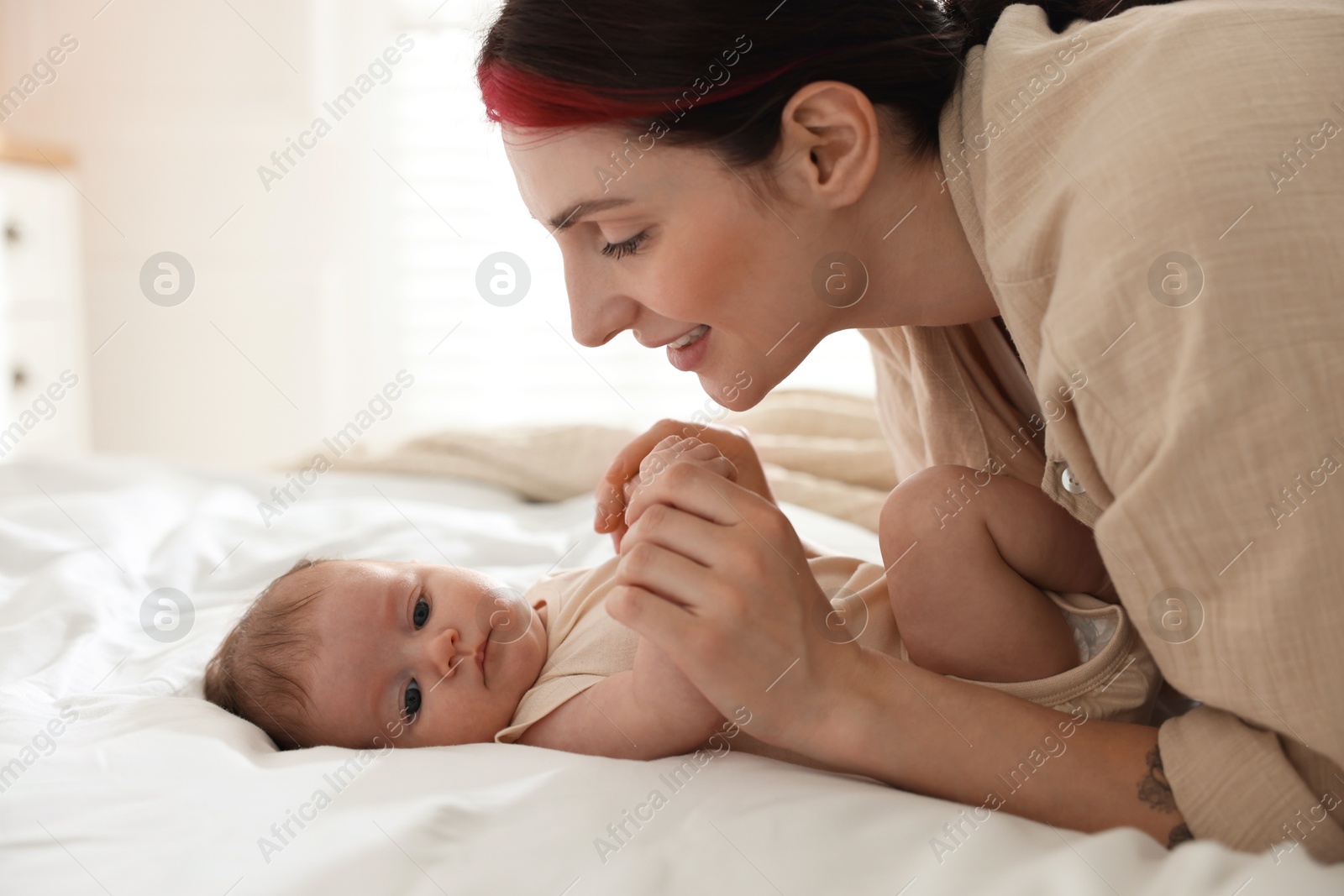 Mother with her newborn baby on bed indoors Photo of Mother with her newborn baby on bed indoors