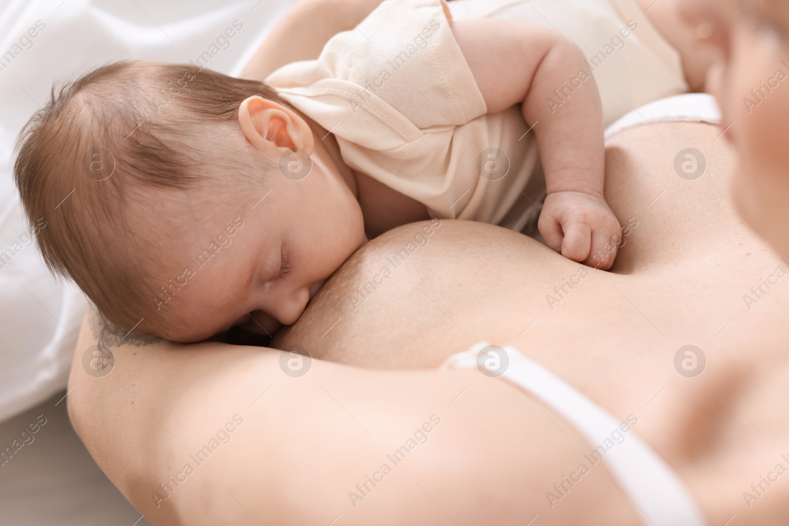 Mother breastfeeding her newborn baby indoors, above view Photo of Mother breastfeeding her newborn baby indoors, above view