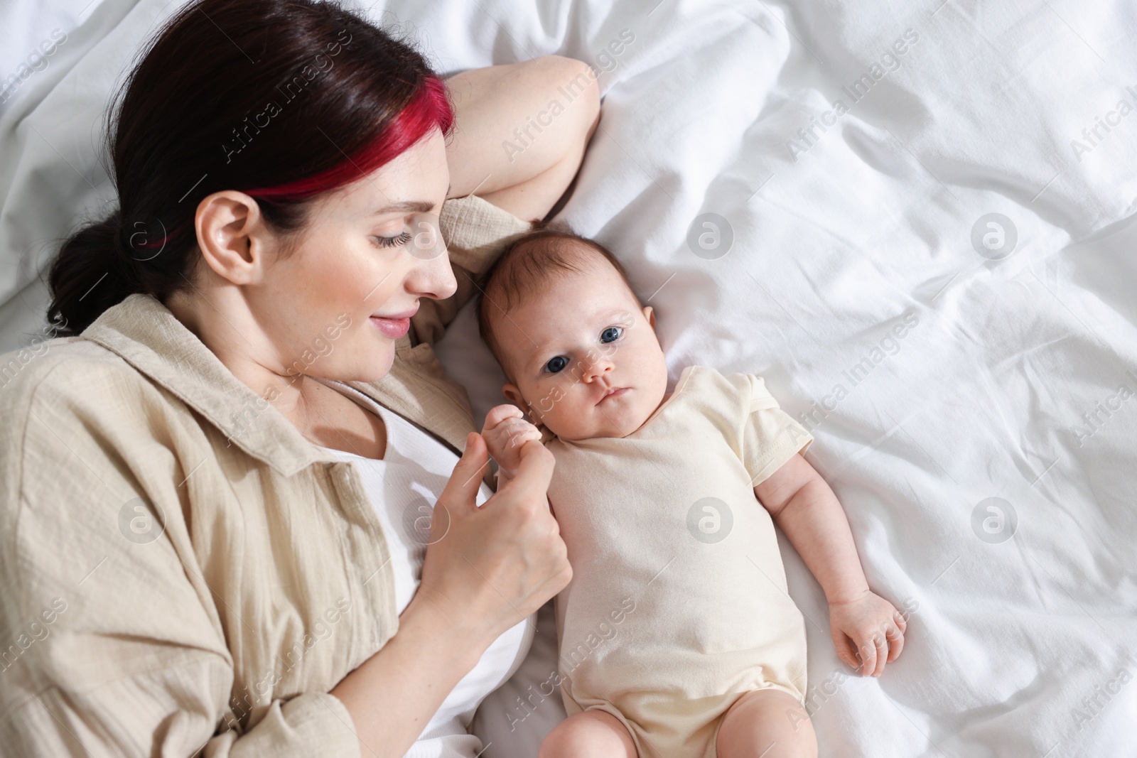 Mother with her newborn baby on bed indoors, top view. Space for text Photo of Mother with her newborn baby on bed indoors, top view. Space for text